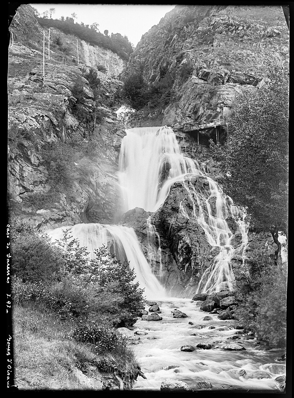 Photo ancienne (noir et blanc, format portrait, 2448x3314, 1,6 Mo) de la cascade de Sarenne, prise entre 1890 et 1914. Page Commons : https://commons.wikimedia.