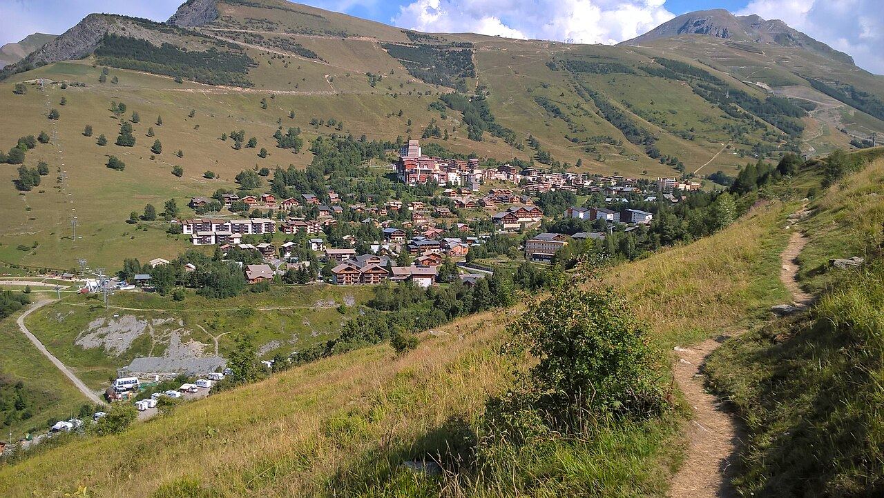 La station des 2 Alpes en été, vue depuis un sentier de montagne au milieu des prairies
