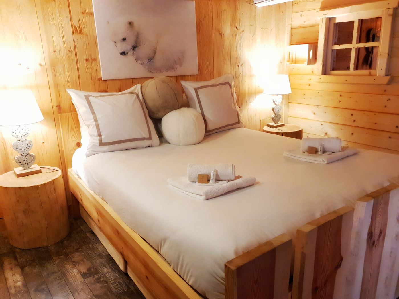Schlafzimmer mit großem Bett, weißer Bettwäsche und hellem Holz