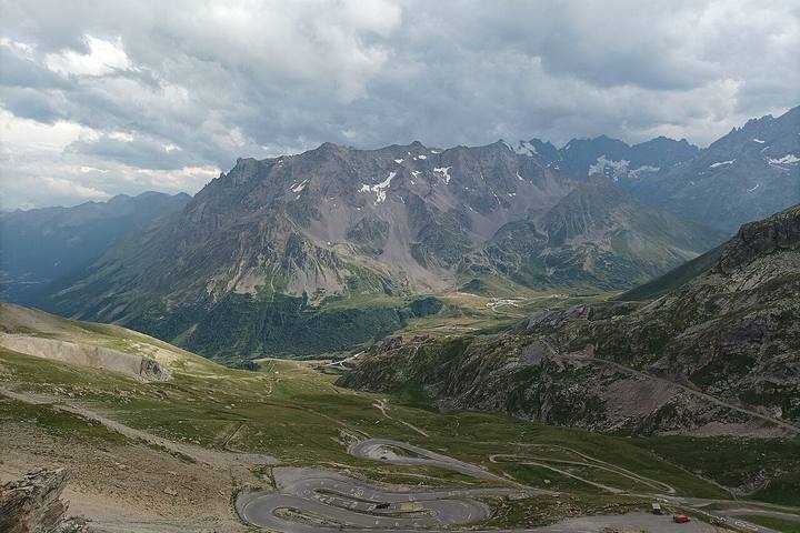 Vue du sommet du Galibier sur les lacets de la route et le col du Lautaret, sous un ciel chargé