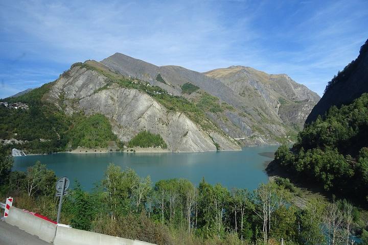 Le lac du Chambon, eau turquoise et versants gris, vu depuis la D213 qui monte aux 2 Alpes