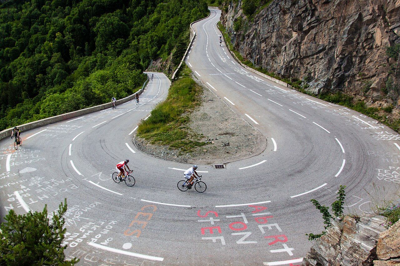 Cyclistes dans une épingle de l'Alpe d'Huez, sur un bitume couvert de noms peints par les supporters