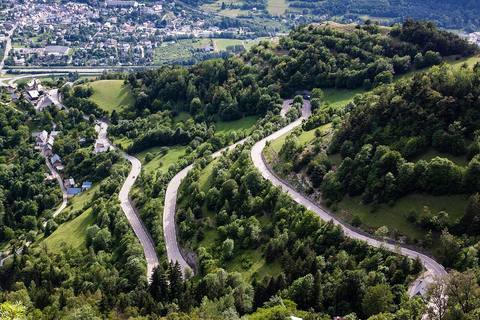 Vue plongeante sur les lacets de la D211 dans la forêt, avec Le Bourg-d'Oisans au fond de la vallée
