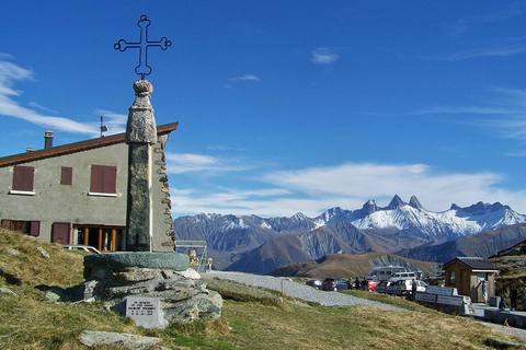 Sommet du col de la Croix de Fer : la croix sur son pilier de pierre, le chalet et les Aiguilles d'Arves enneigées