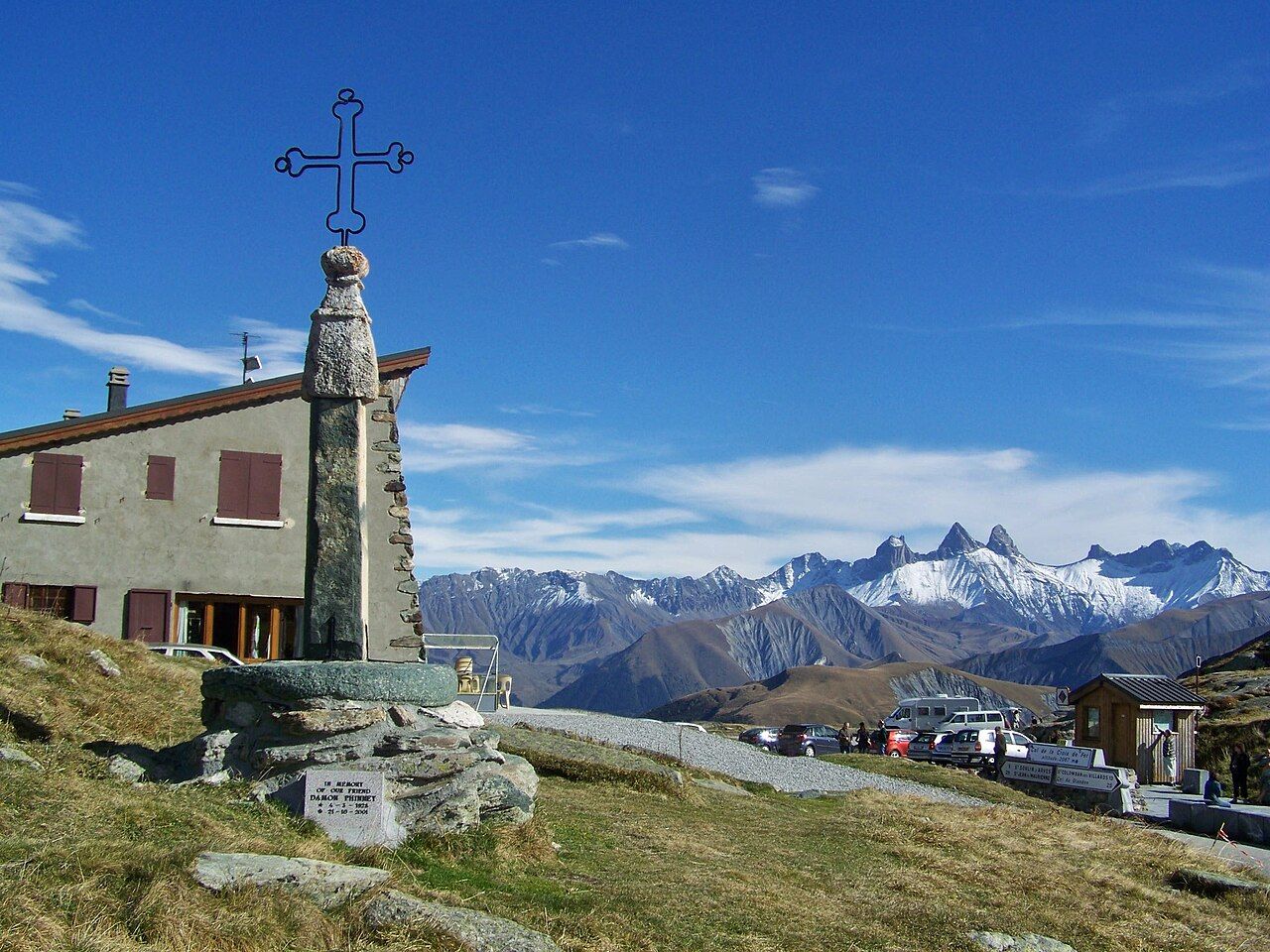 Sommet du col de la Croix de Fer : la croix sur son pilier de pierre, le chalet et les Aiguilles d'Arves enneigées