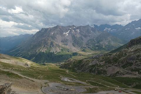 Vue du sommet du Galibier sur les lacets de la route et le col du Lautaret, sous un ciel chargé