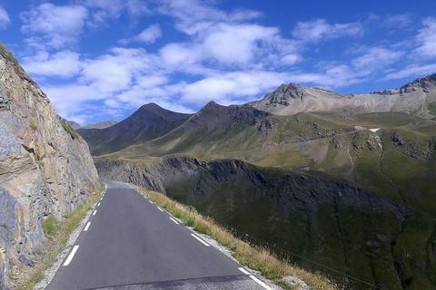 La route étroite du Galibier longe une paroi rocheuse au-dessus des alpages, côté Hautes-Alpes