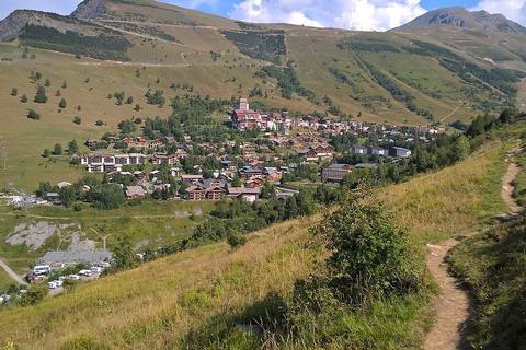 La station des 2 Alpes en été vue depuis un sentier, chalets et immeubles au pied des alpages