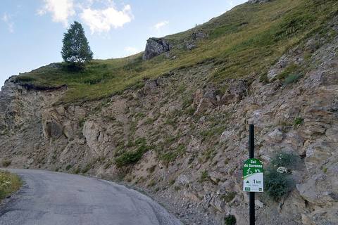 Panneau cycliste du col de Sarenne indiquant 1 km à 9 % à 1 909 m, au bord de la route étroite taillée dans la roche