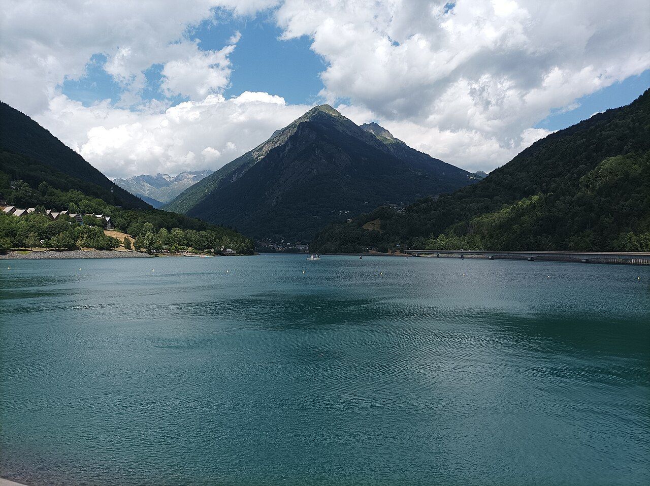 Le lac du Verney aux eaux turquoise vu depuis le barrage, avec à droite le viaduc de la D526 qui longe le lac