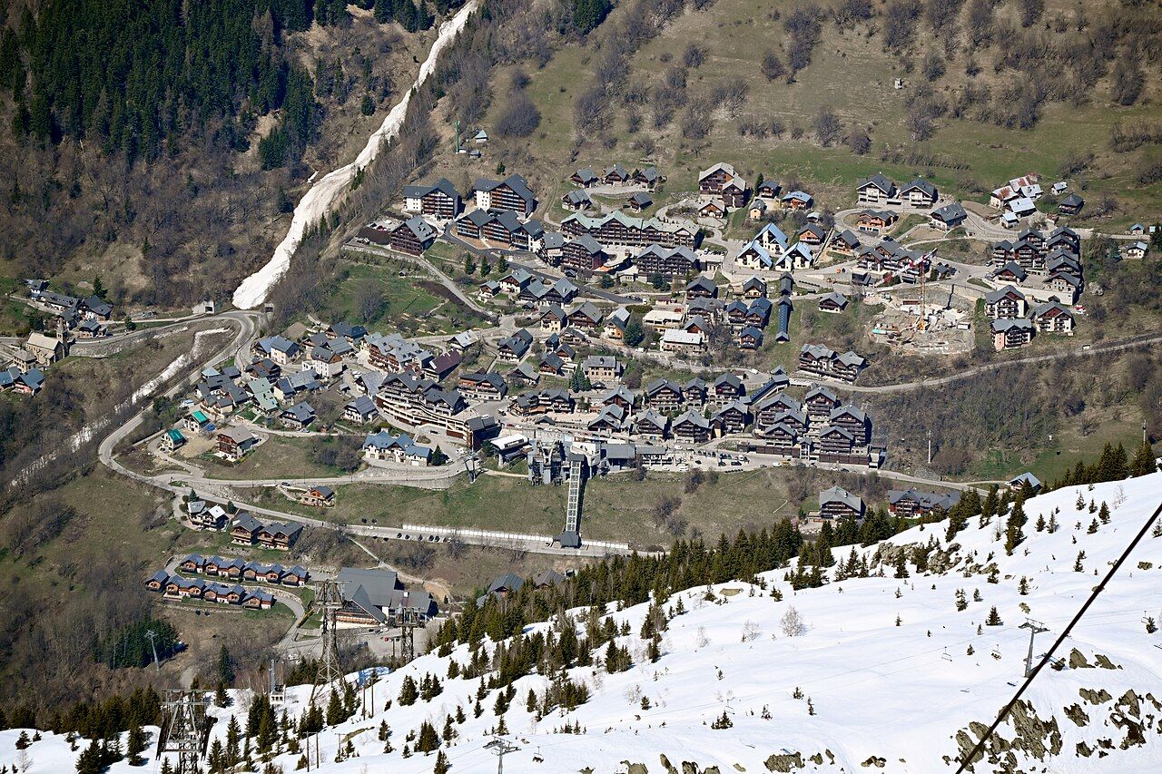 Vaujany vu d'en haut au printemps, ses chalets, la gare du téléphérique et la route du village, neige au premier plan